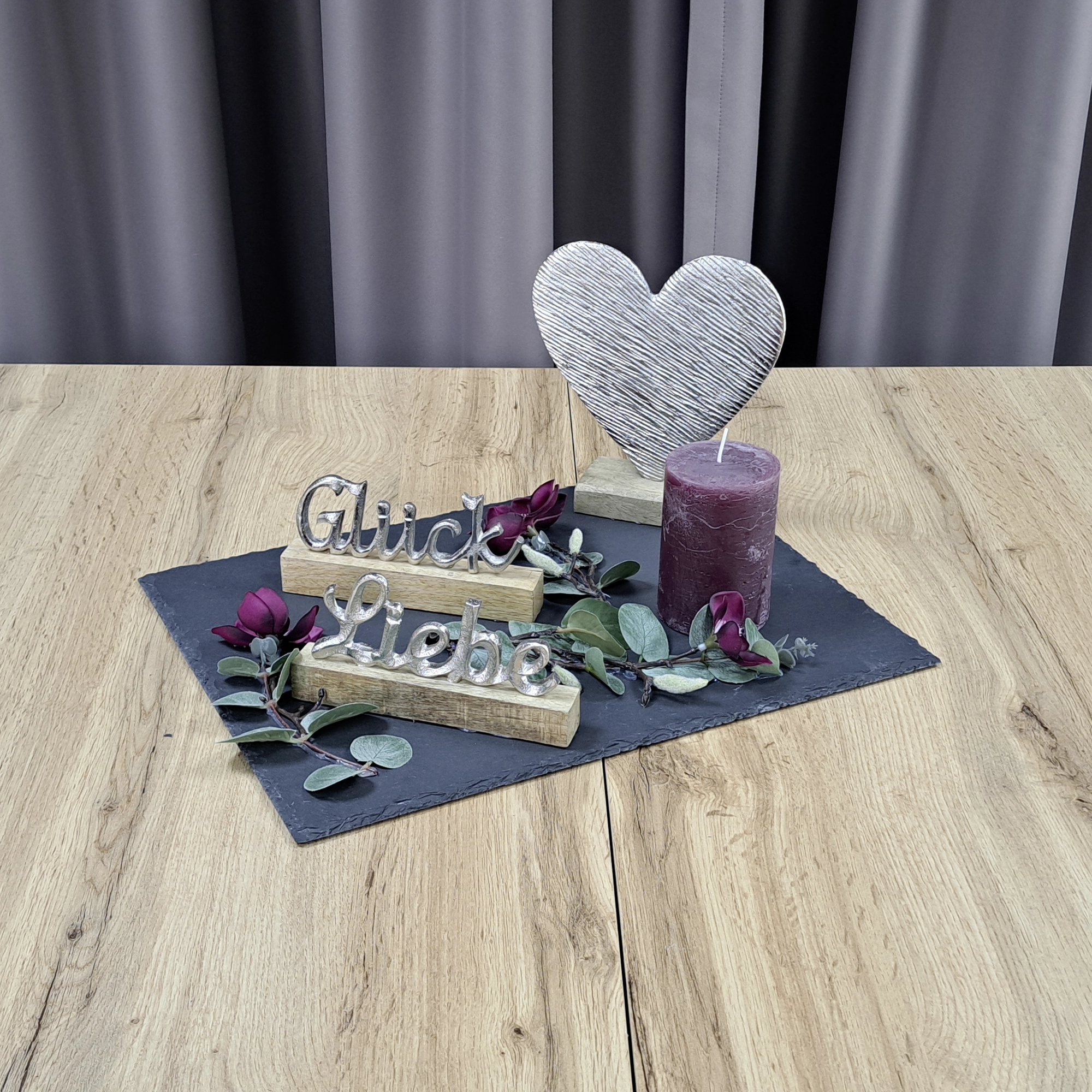 Décoration en forme de cœur : cœur argenté avec une bougie, de l’eucalyptus et des inscriptions, pour une décoration de table pleine de tendresse
