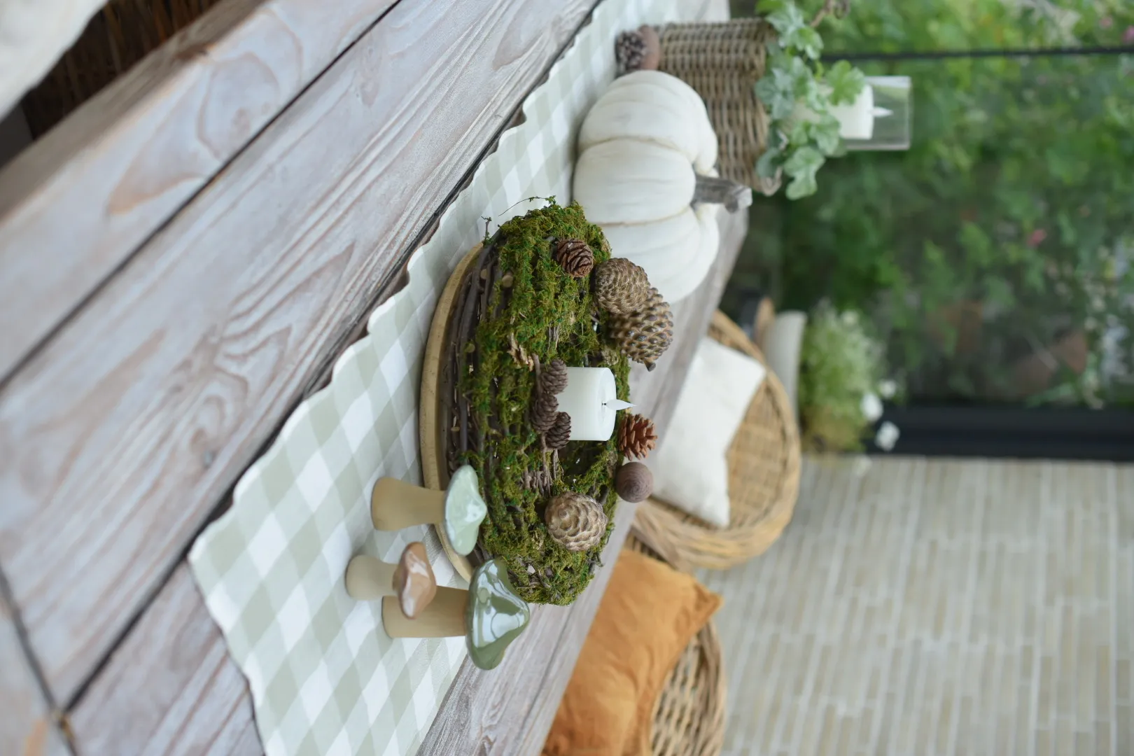 Décoration d'automne : couronne de mousse avec des pommes de pin, une bougie et des champignons en céramique, pour une décoration de table naturelle