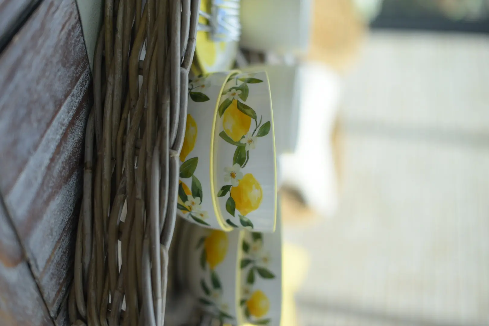 Vaisselle : bol en céramique blanche orné d'un motif de citrons, présenté dans un panier en rotin tressé, pour une décoration de table estivale