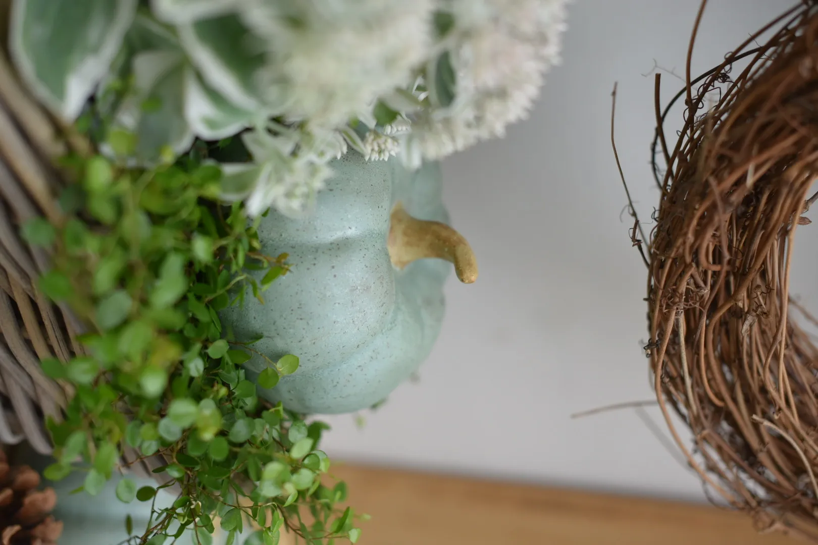 Décoration d'automne : citrouille en céramique verte avec une couronne naturelle et des fleurs blanches comme décoration de table