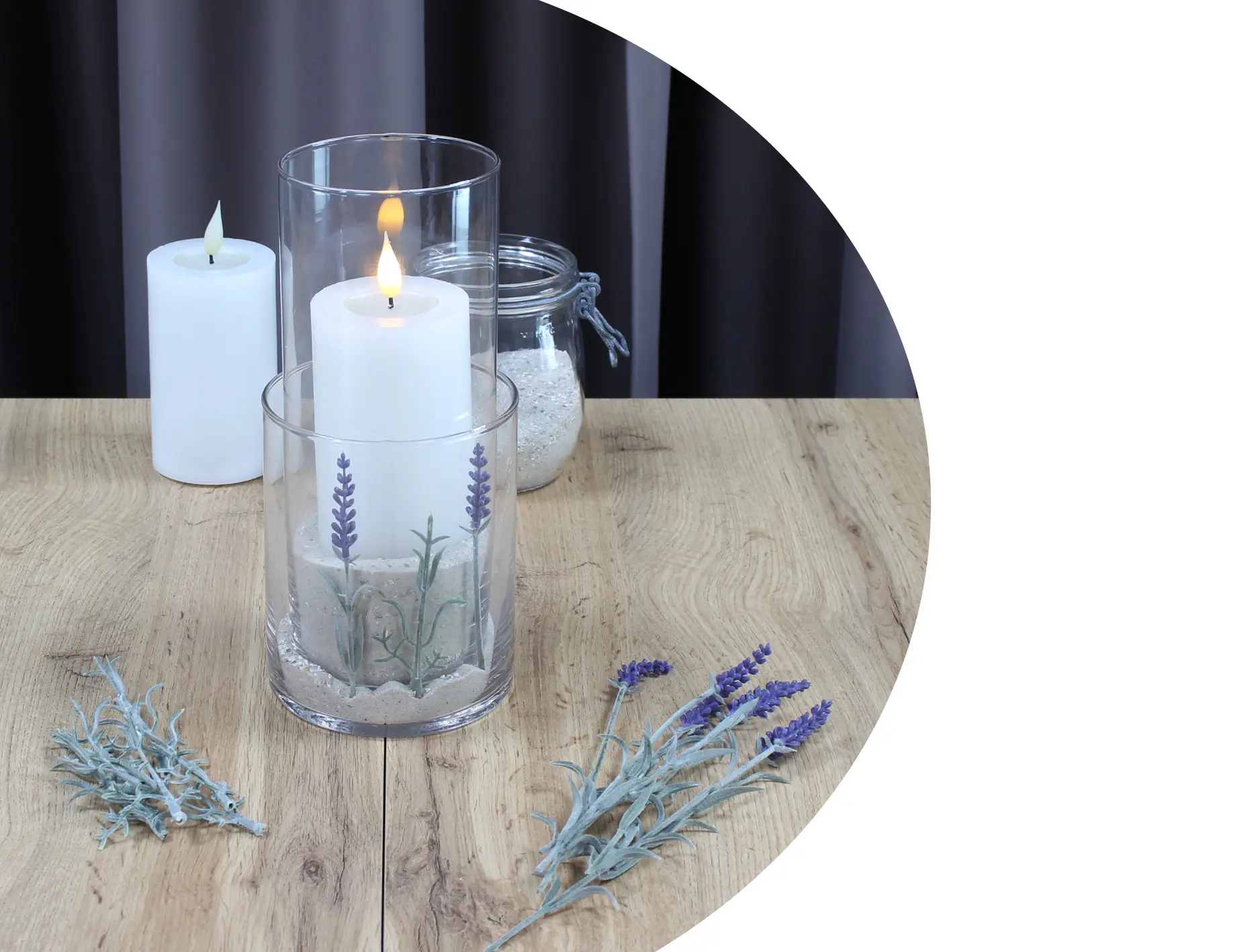 Décoration avec bougie : récipient en verre avec une bougie blanche, du sable et un motif de lavande pour une décoration de table provençale