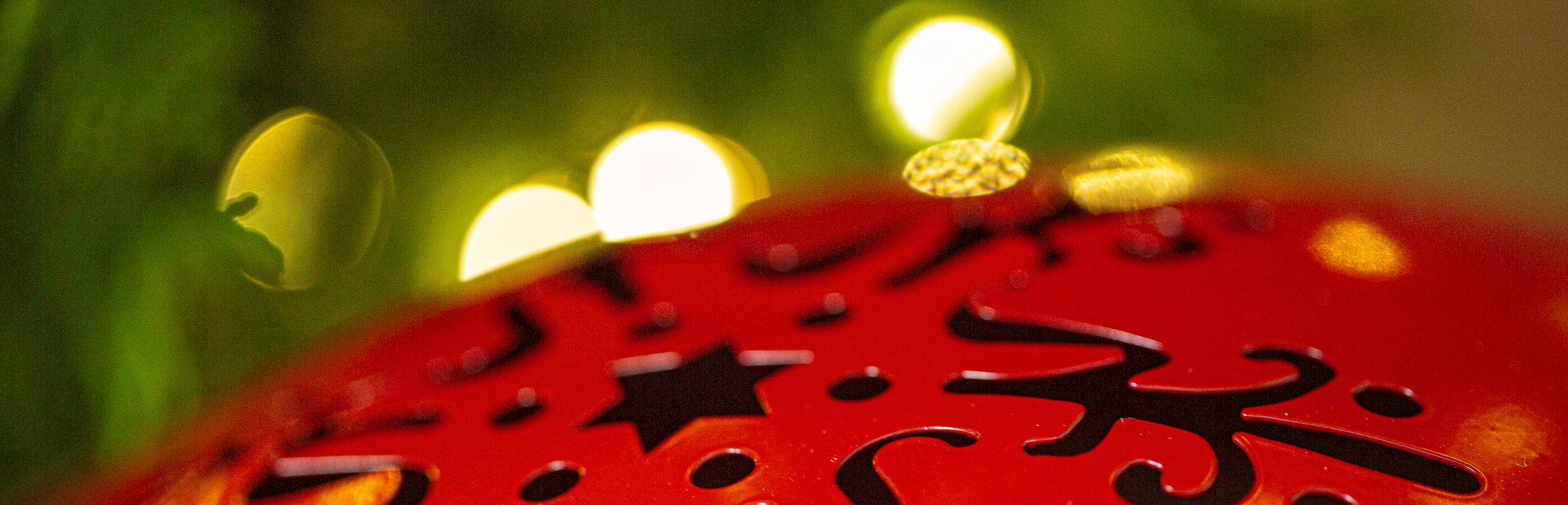 Décoration de Noël : boule métallique rouge ornée d'étoiles et de lumières chaleureuses, pour une décoration festive