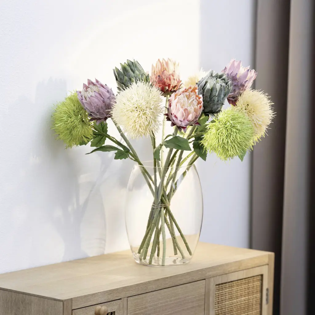 Bouquet coloré de protéas dans un vase en verre posé sur un buffet