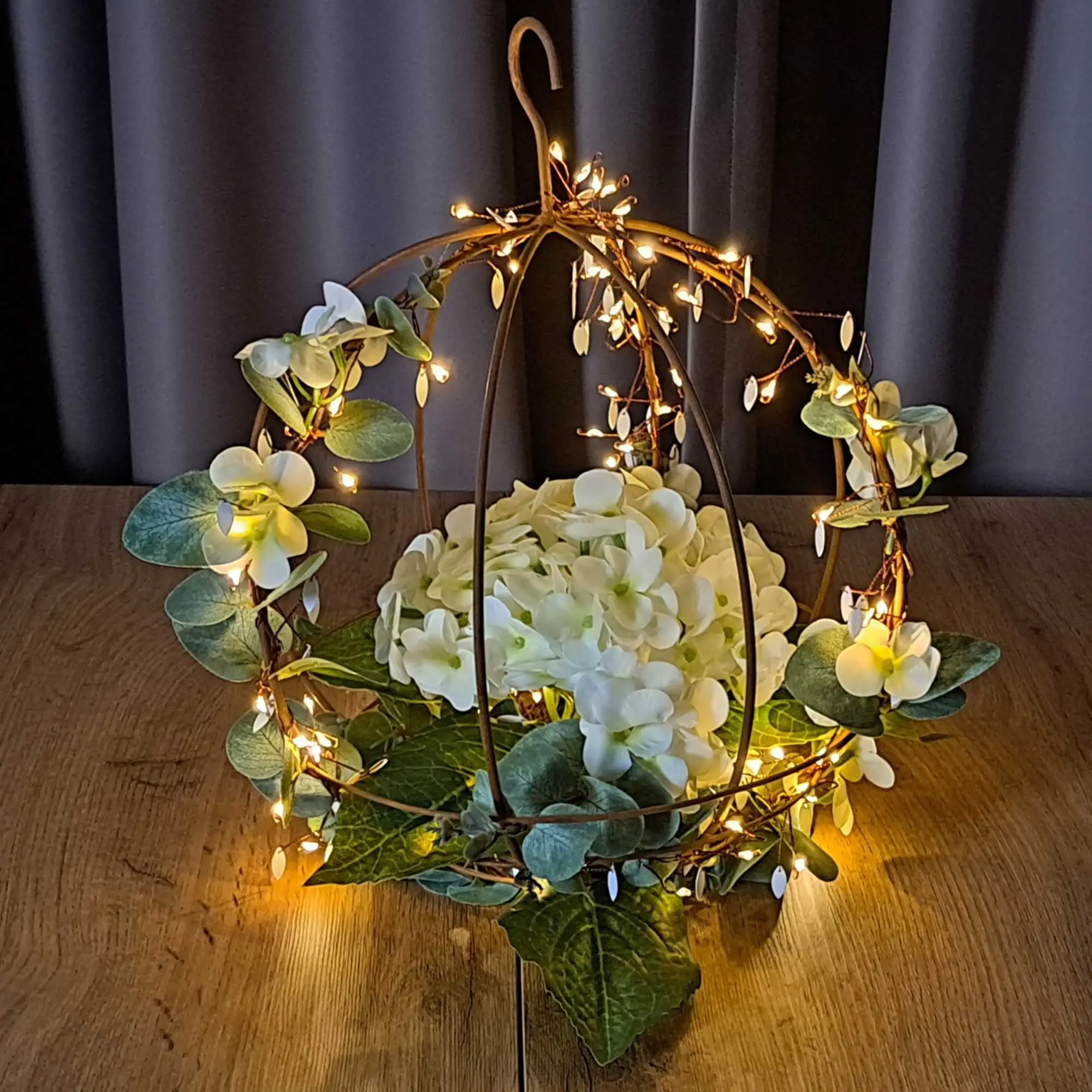Décoration lumineuse LED : boule suspendue en métal avec guirlande lumineuse aux couleurs chaudes, fleurs blanches et feuilles vertes