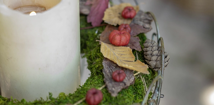 Décoration d'automne : une bougie agrémentée de mousse, de feuilles et de petites citrouilles pour une décoration nostalgique