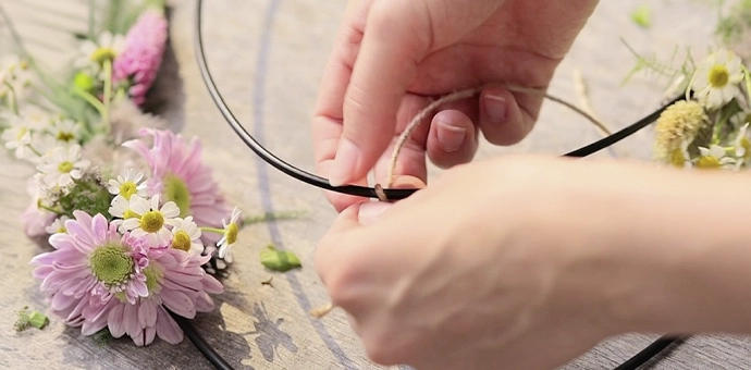 Décoration DIY : anneau métallique, ruban de jute et fleurs roses comme accessoires pour créer soi-même une couronne décorative
