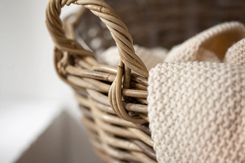 Aufbewahrungskörbe: naturfarbener Rattankorb mit cremefarbener Strickdecke als Wohnraumdeko