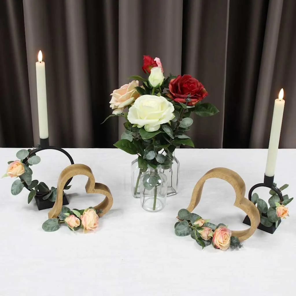 Décoration de table : bouquet de roses dans des vases en verre, avec des cœurs en bois et des bougies cylindriques pour une ambiance romantique