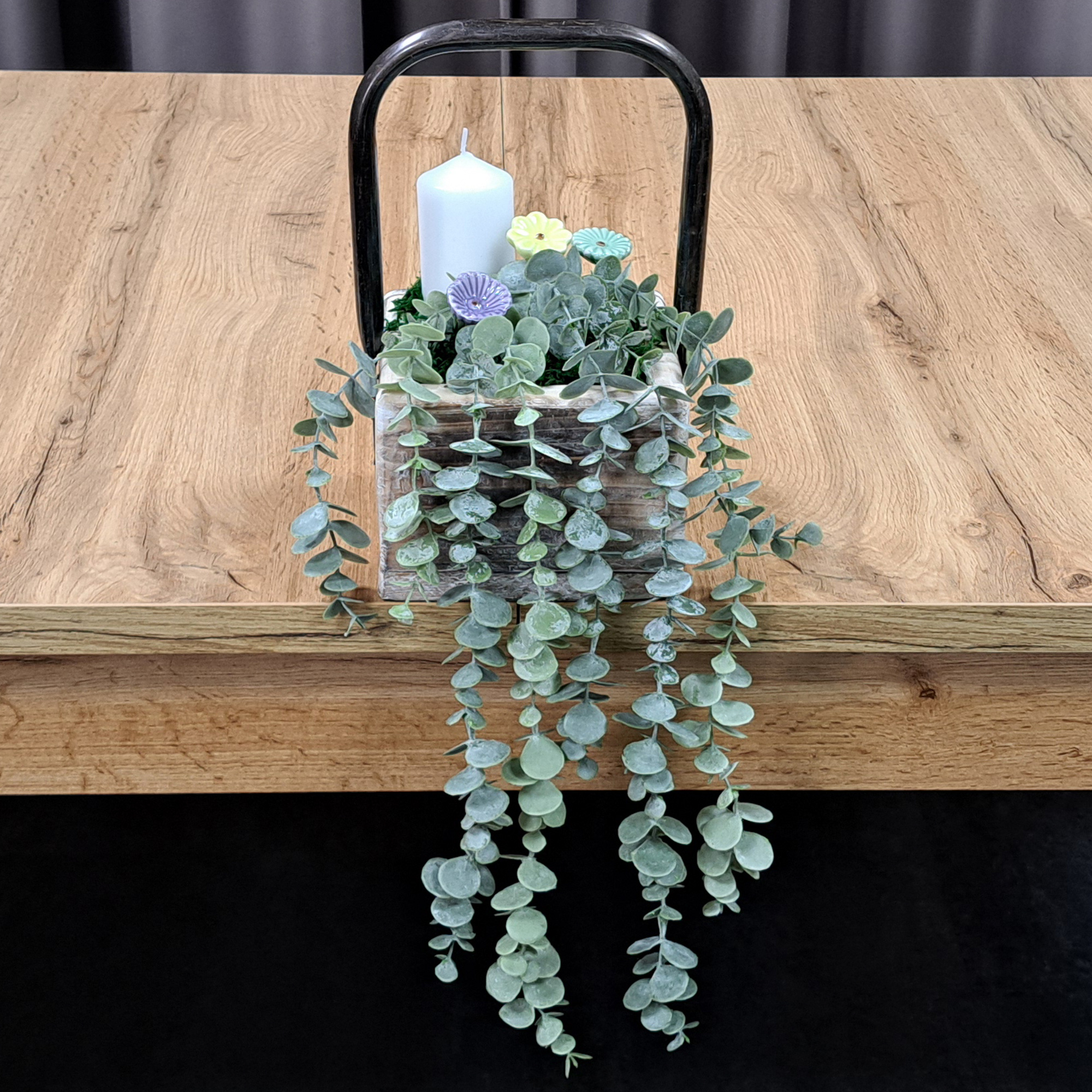 Décoration à la bougie : récipient en bois avec une bougie blanche et de l'eucalyptus, une décoration de table naturelle