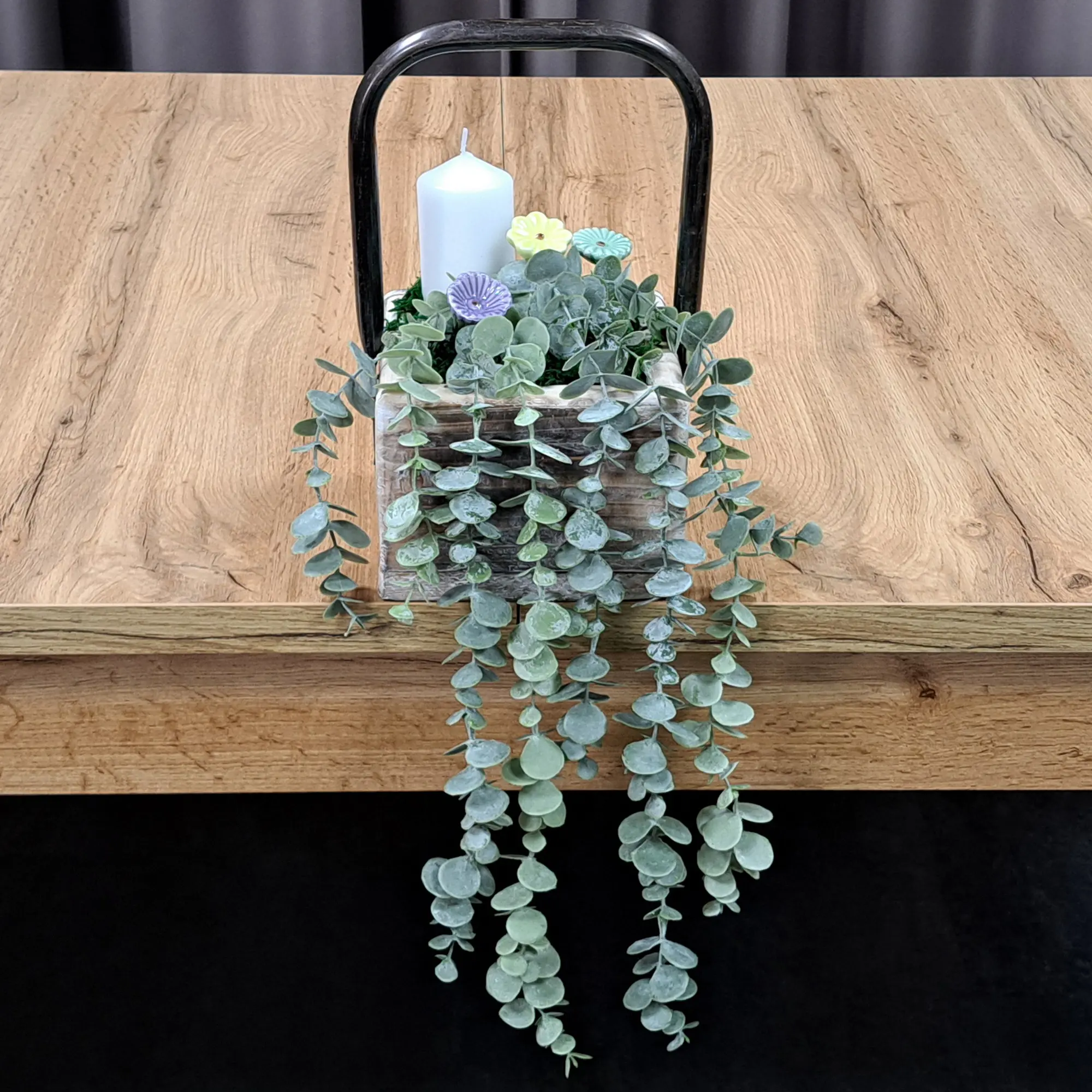 Décoration à la bougie : récipient en bois avec une bougie blanche et de l'eucalyptus, une décoration de table naturelle