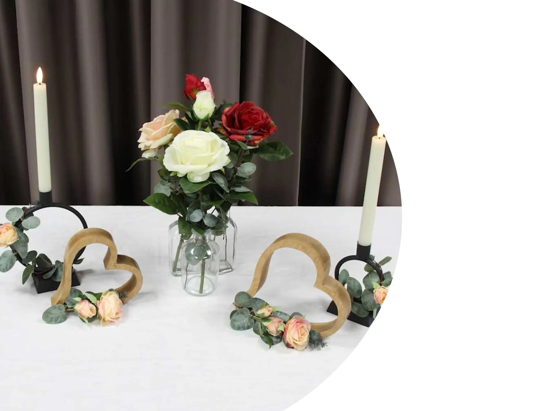 Décoration de table : vase en verre avec des roses colorées, des cœurs en bois et des bougies pour une ambiance romantique