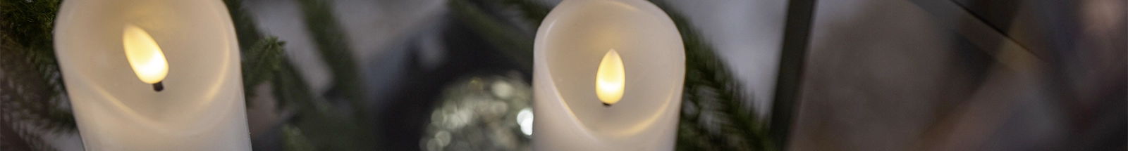 Décoration lumineuse LED : des bougies LED blanches disposées parmi le feuillage de sapin pour une décoration pleine de charme
