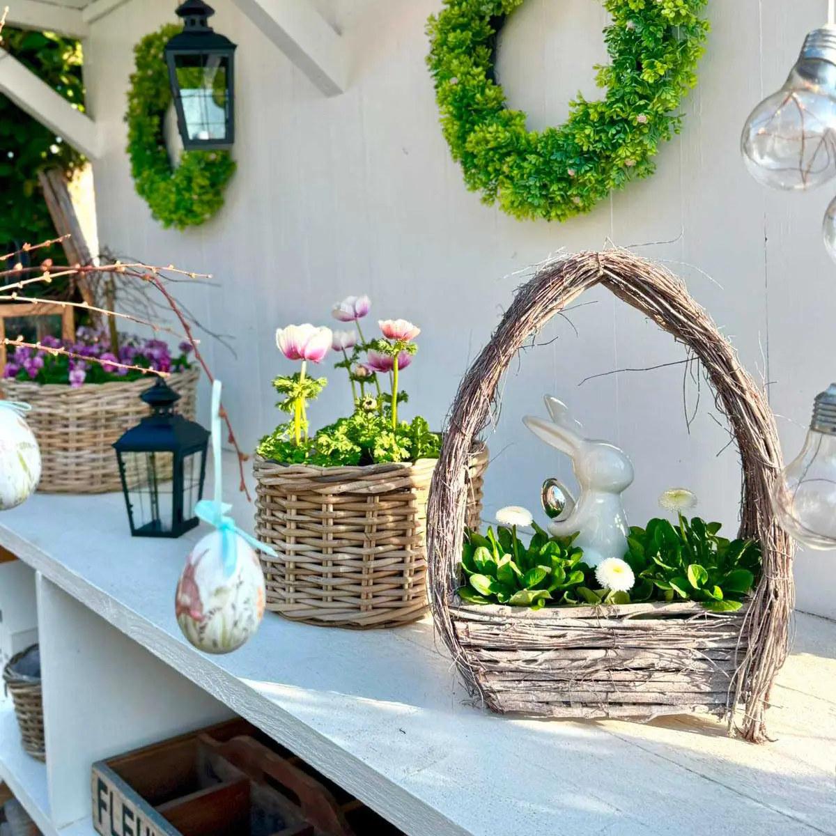 Décoration de Pâques : panier en osier avec figurine de lapin blanche et fleurs printanières, pour une décoration de jardin naturelle