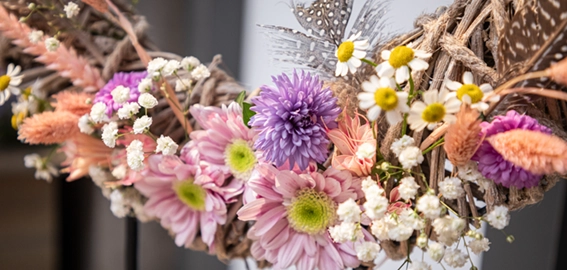 Décoration printanière : couronne aux couleurs naturelles avec des fleurs artificielles roses, violettes et blanches, pour une décoration de Pâques colorée