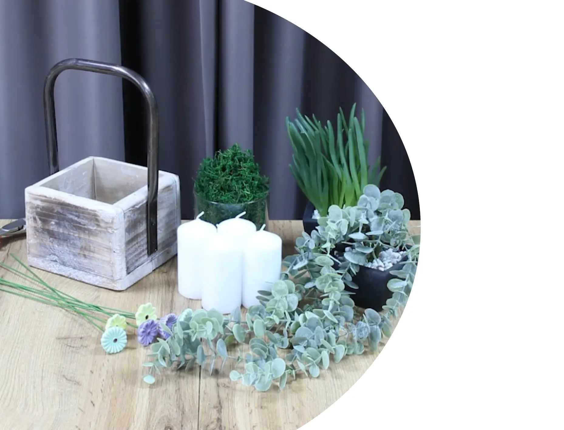 Décoration à base de bougies : récipient en bois avec des bougies blanches, de l'eucalyptus et des plantes vertes, pour une décoration de table naturelle