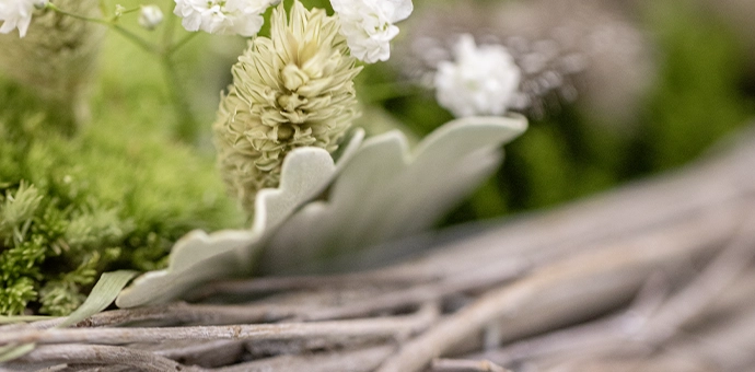 Décoration naturelle : branches tressées agrémentées de mousse verte et de fleurs blanches pour une décoration printanière