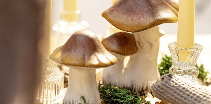 Décoration d'automne : des champignons en céramique agrémentés de mousse et de bougies cylindriques pour une décoration de table naturelle aux tons chauds et naturels