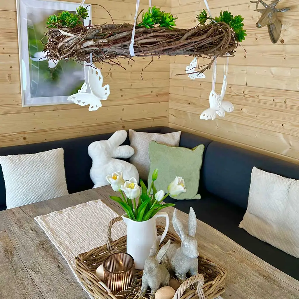 Décoration de Pâques : table de style champêtre avec des figurines de lapins, des tulipes, un plateau en osier et des matériaux naturels