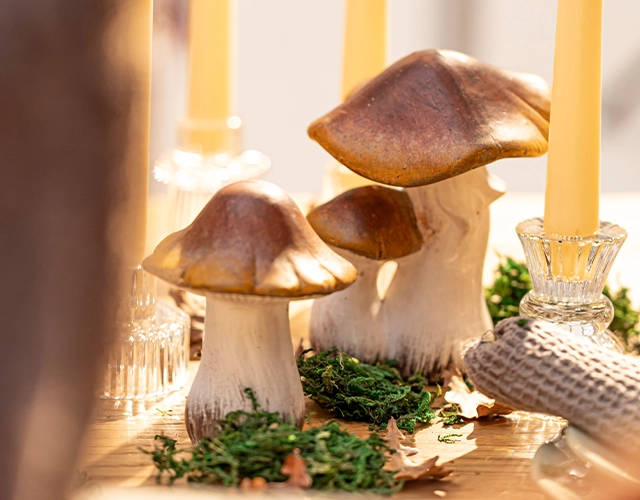 Décoration d'automne : des champignons en céramique avec de la mousse et des bougies cylindriques pour une décoration de table naturelle