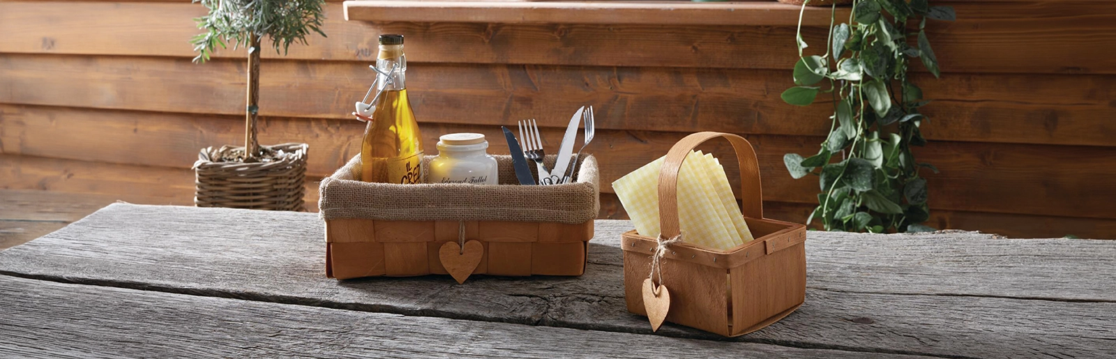Panier de pique-nique : panier en bois contenant des couverts, une bouteille et des serviettes, pour une décoration de table rustique dans le style chalet