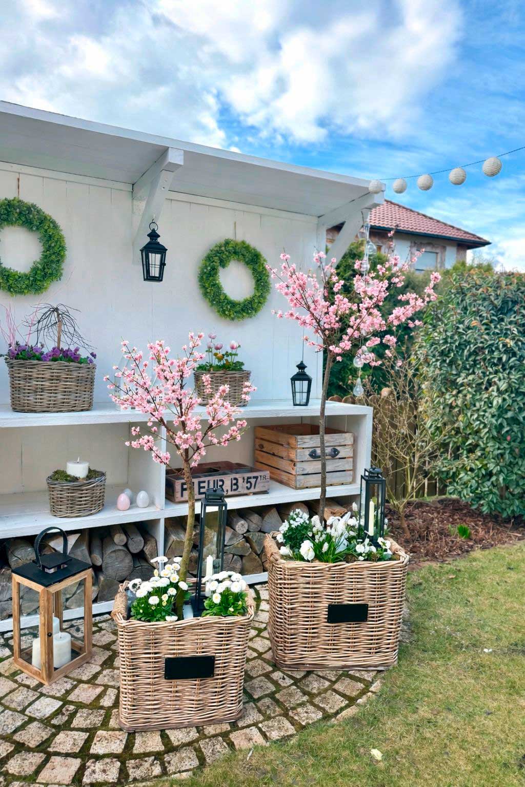 Gartendeko: große Weidenkörbe mit Kirschblüten und Frühlingsblumen als Außendekoration