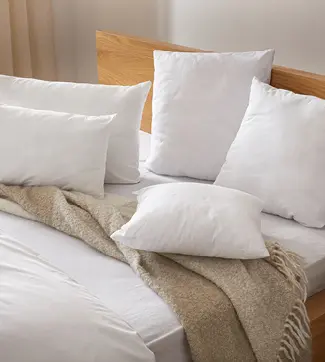 Nahaufnahme eines Betts mit weißen Kissen und naturfarbener Decke