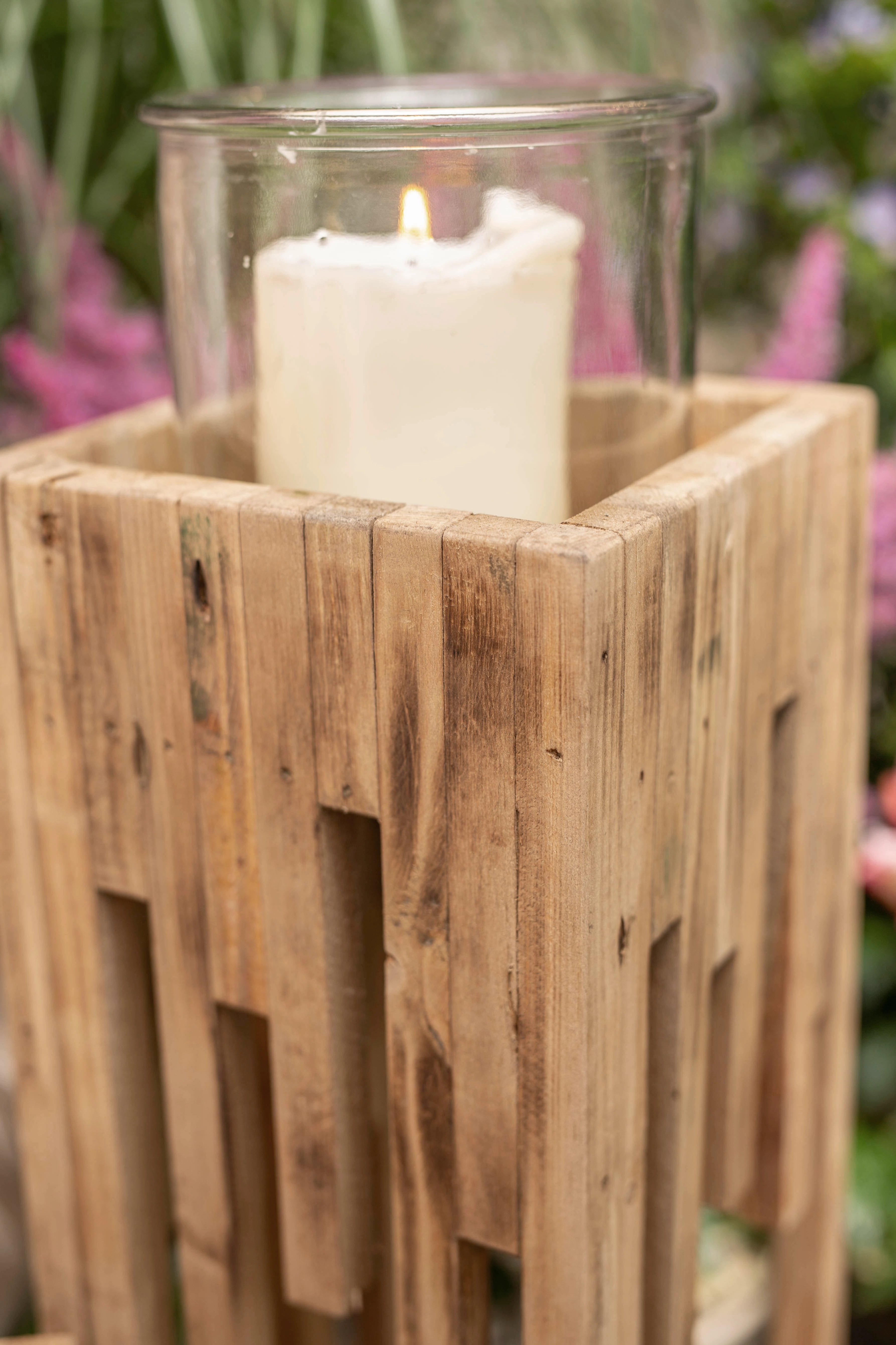 Lanterne rustique en bois avec insert en verre et bougie allumée, sur fond floral dans une décoration automnale